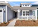 Inviting covered porch showcasing decorative columns, a white railing, and manicured landscaping at 4996 Song Sparrow Way, Summerville, SC 29483