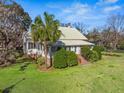 Charming home with lush landscaping, including palm trees, a covered front porch, and an inviting entrance at 901 Morton Waring Ln, Pinopolis, SC 29469