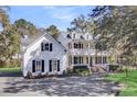 Elegant two-story white home with classic black shutters and a sprawling driveway, exuding curb appeal at 100 Oak Village Ln, Summerville, SC 29483