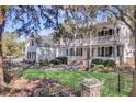 Stately white home with a welcoming double porch, black shutters, and lush green lawn enclosed by a black fence at 100 Oak Village Ln, Summerville, SC 29483