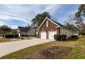 View of a two-car garage featuring a brick exterior with black shutters, a concrete driveway, and mature trees at 109 Presidio Bnd, Summerville, SC 29483