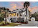 Elegant two-story white home with covered porch, complimented by palm trees and meticulous landscaping at 129 Sparrow Dr, Isle of Palms, SC 29451