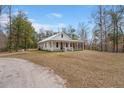 Quaint single-story home features a white exterior, metal roof, a welcoming porch and screened in side porch at 5585 Wire Road, Branchville, SC 29432