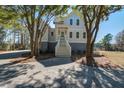 Beautiful two-story home with stairs leading up to porch and mature trees at 7527 Ladys Secret Ln, Awendaw, SC 29429