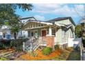 Street view of inviting home featuring a landscaped yard, front porch, and eye-catching brick foundation at 12 Poplar St, Charleston, SC 29403