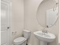 Stylish half-bathroom with a pedestal sink, oval mirror, and modern fixtures, adjacent to a door at 1832 Nola Run, Summerville, SC 29485