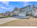 Stunning two-story home featuring a balcony, covered porch, a two-car garage, and a long driveway at 207 Calm Water Way, Summerville, SC 29486