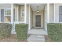 Front door featuring an elegant overhead light fixture, dark door, white railing, and large bushes at 249 Brookshire Rd, Goose Creek, SC 29445