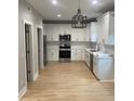 Modern kitchen with white cabinets, stainless steel appliances, stylish light fixture, and bright countertops at Ln, Walterboro, SC 29488