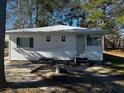 Quaint home with white siding, green shutters, and metal roof, nestled in a serene, tree-lined neighborhood at 1202 Forty-One Rd, Saint Stephen, SC 29479