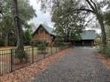 Charming log cabin home with a two-car garage and a gravel driveway surrounded by trees at 2407 Edisto Ferry Rd, Edisto Island, SC 29438