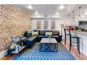 Modern living room featuring exposed brick, comfortable seating, stylish decor, and a view into the kitchen at 377 King St # 203, Charleston, SC 29401