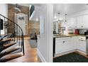 A cozy living room featuring hardwood floors, a spiral staircase, and a view into the kitchen with granite countertops at 377 King St # 203, Charleston, SC 29401