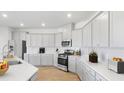 Bright, modern kitchen featuring white cabinets, stainless steel appliances, quartz countertops, and hardwood floors at 562 Richfield Way, Summerville, SC 29486