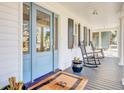 Close-up of a charming front porch, featuring classic rocking chairs and a welcoming blue front door at 1048 Wharf Indigo Pl, Mount Pleasant, SC 29464
