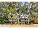 Charming two-story home with a large tree providing shade and a covered porch for enjoying the outdoors at 1429 Burningtree Rd, Charleston, SC 29412