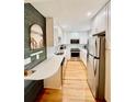 Modern kitchen featuring stainless steel appliances, white cabinets and hardwood floors at 2 Sandcrab Ct, Isle of Palms, SC 29451