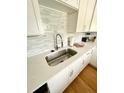 Bright kitchen featuring white cabinets, light countertops, stylish backsplash, and stainless steel sink at 2 Sandcrab Ct, Isle of Palms, SC 29451