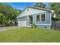 Quaint blue home showcasing a lush green lawn, tidy landscaping, and an attached one-car garage at 1565 Juniper St, Charleston, SC 29407