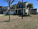 Two-story home with a gray exterior, palm trees, a front porch with white columns, and an attached garage at 3072 Adventure Way, Ladson, SC 29456
