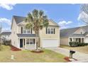 Charming two-story home featuring a palm tree, black shutters, a front porch, and a two-car garage at 315 Bradley Bend Dr, Moncks Corner, SC 29461