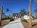 Eye-level view of a white home with a long driveway framed by palmetto trees and a three-car garage at 3949 Bulow Landing Rd, Ravenel, SC 29470