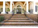 Inviting front porch with brick steps, black railings and arched entryway at 65 Surfsong Rd, Kiawah Island, SC 29455