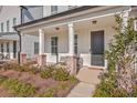 Inviting front porch with brick accents, comfortable seating, and a stylish black front door at 131 Summer Tanager Dr, Ravenel, SC 29470