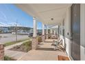 Covered front porch featuring brick pillars and a cozy seating area with views of the neighborhood at 131 Summer Tanager Dr, Ravenel, SC 29470