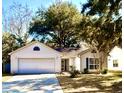 Inviting single-story home featuring a two-car garage, a manicured lawn, and mature trees at 2421 Castlereagh Rd, Charleston, SC 29414