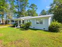 Well-maintained single-story home featuring a metal roof, white trim, and verdant, landscaped grounds at 422 Academy Rd, Walterboro, SC 29488