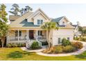 Charming two-story home features a quaint porch, manicured lawn, and elegant landscaping at 4343 Ten Shillings Way, Ravenel, SC 29470