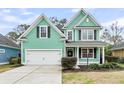 Inviting two-story home featuring green siding, black shutters, manicured landscaping, and a two-car garage at 2085 Terrabrook Ln, Charleston, SC 29412
