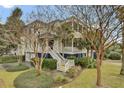 Inviting two-story home with a welcoming front porch and stairs nestled among beautiful trees and landscaping at 4000 Cameron Blvd, Isle of Palms, SC 29451