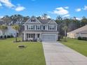 Beautiful two-story home with manicured lawn and palm trees, long driveway leading to garage at 502 Pontoon Rd, Huger, SC 29450