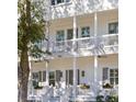 Inviting white home featuring a double porch, accentuated by gray shutters and hanging plants at 610 Daggett St, Daniel Island, SC 29492