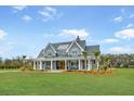 Charming two-story home with a spacious front porch, rocking chairs, manicured lawn, and beautiful curb appeal at 2621 Anchor Watch Dr, Wadmalaw Island, SC 29487