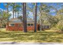 View of backyard showing exterior brick, mature trees, and healthy grass lawn at 407 Hayne St, Walterboro, SC 29488