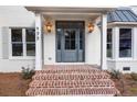 Inviting front porch with brick steps, stylish gray door, and decorative lanterns for a warm welcome at 499 Lackland Ct, Mount Pleasant, SC 29464