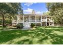 Traditional two story home with a backyard featuring a large, covered porch with a stone fireplace at 5991 Joseph Blake Ln, Wadmalaw Island, SC 29487