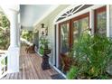 Cozy front porch with wood floors, potted plants, wicker furniture and a beautiful wood door at 5991 Joseph Blake Ln, Wadmalaw Island, SC 29487