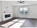 An empty living room has a ceiling fan, fireplace, hardwood floors and a window overlooking trees at 669 Silver Spruce St, Summerville, SC 29486