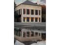 A close exterior view of a cream-colored two-story building with striking black shutters and a reflection in a puddle at 90 E Bay St, Charleston, SC 29401