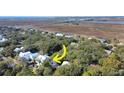 An aerial view of a home nestled in a lush, wooded landscape, featuring white exterior and marsh views at 2514 Myrtle Ave, Sullivans Island, SC 29482