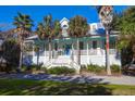 Charming two-story home with a welcoming front porch and beautiful palm trees at 2514 Myrtle Ave, Sullivans Island, SC 29482