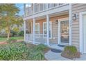 Close up on the front door and front porch of a two-story home with green landscaping at 339 Cicadas Song, Moncks Corner, SC 29461