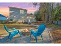 Cozy backyard featuring a stone fire pit with two blue Adirondack chairs, a stone pathway, and wooded perimeter at 1253 Lakefront Dr, Charleston, SC 29412