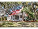 Charming home with screened porch, red roof, and lush landscaping at 127 Oak St, McClellanville, SC 29458