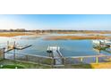 High-angle view of wooden dock with boats, calm water, and marshland, enclosed by a fenced yard at 1614 Teal Marsh Rd, Charleston, SC 29412