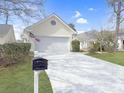 Charming one-story home featuring a two-car garage, manicured lawn, and a long driveway at 2419 Tuscany Dr, North Charleston, SC 29406